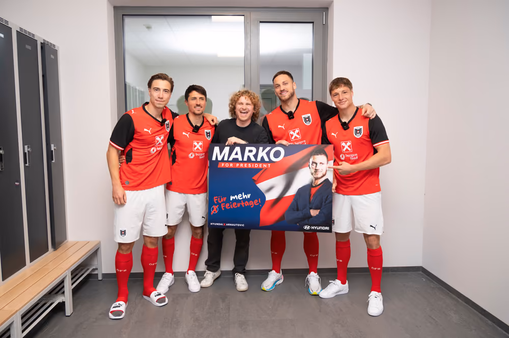Gruppenfoto in der Kabine: Spieler und ein Teammitglied halten das „Marko for President“-Plakat